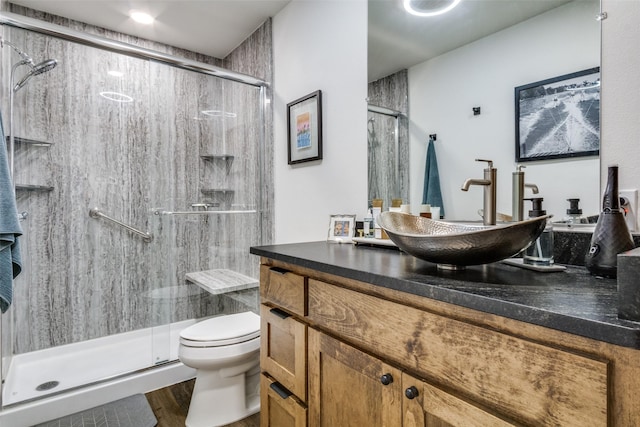 bathroom featuring a stall shower, vanity, toilet, and wood finished floors