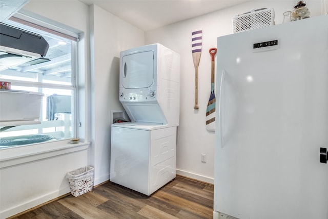 laundry room with stacked washing maching and dryer, laundry area, baseboards, and wood finished floors