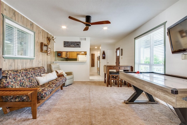rec room featuring wood walls, a ceiling fan, visible vents, and light carpet