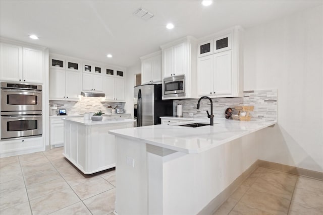 3852 Banner Dr, Frisco, TX 75034 - kitchen with stainless steel appliances, a sink, a peninsula, backsplash, and light tile patterned floors