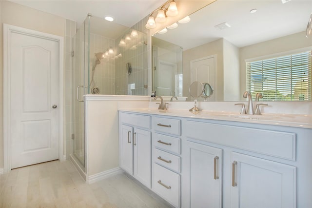 bathroom with wood finished floors, a sink, double vanity, and a stall shower
