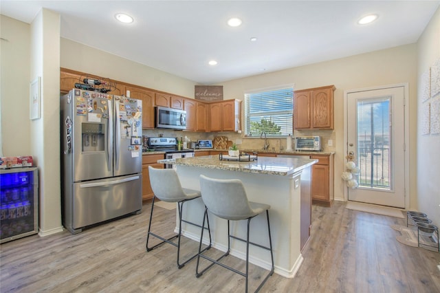 kitchen with light wood finished floors, a toaster, a center island, decorative backsplash, and appliances with stainless steel finishes