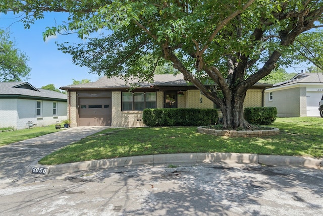view of front of property featuring brick siding, driveway, a front yard, and a garage