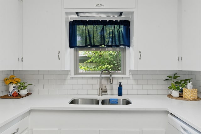 kitchen featuring light countertops, a sink, dishwasher, and white cabinetry