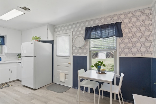 6050 Douglas St, Fort Worth, TX 76114 - kitchen with freestanding refrigerator, wallpapered walls, light wood-style floors, light countertops, and white cabinetry