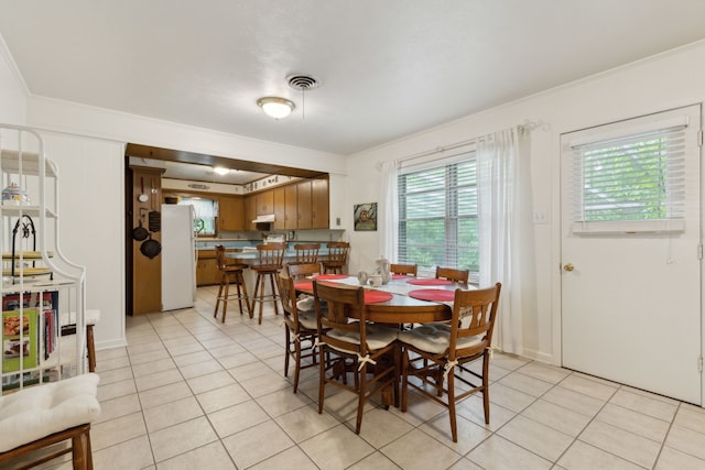 dining room featuring visible vents, a healthy amount of sunlight, ornamental molding, and light tile patterned floors