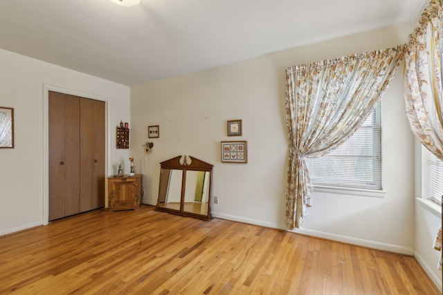bedroom featuring light wood-type flooring, a closet, and baseboards