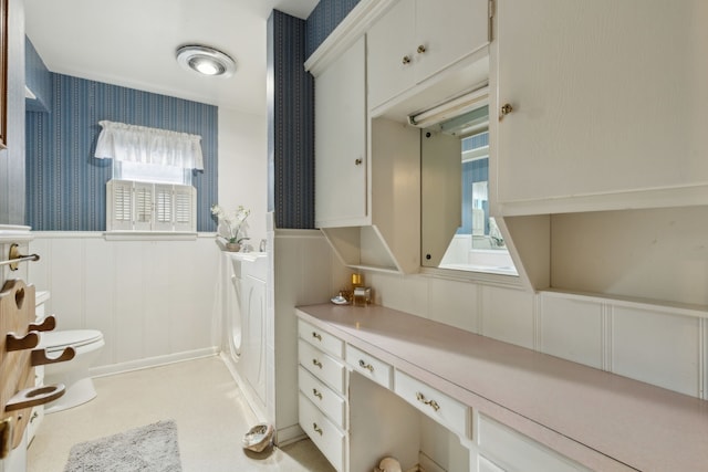 bathroom with toilet, a wainscoted wall, wallpapered walls, and a decorative wall