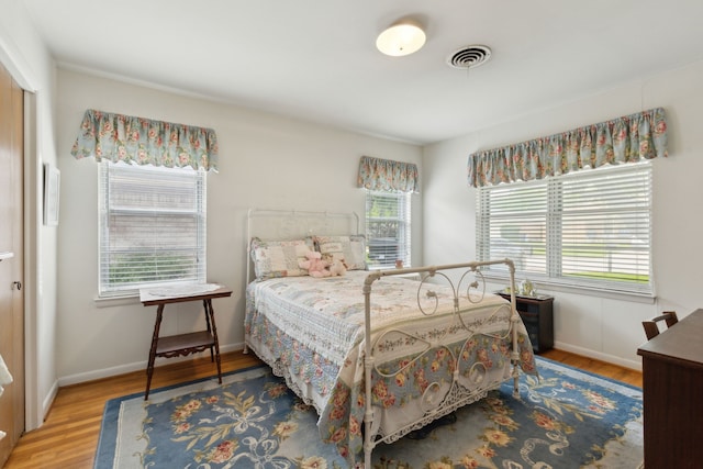 bedroom with baseboards, wood finished floors, and visible vents