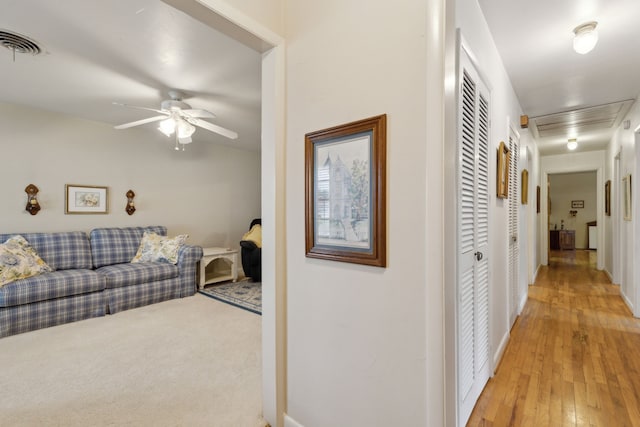 corridor featuring baseboards, visible vents, and light wood-type flooring
