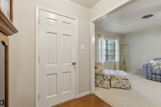 tiled foyer with visible vents, baseboards, and carpet