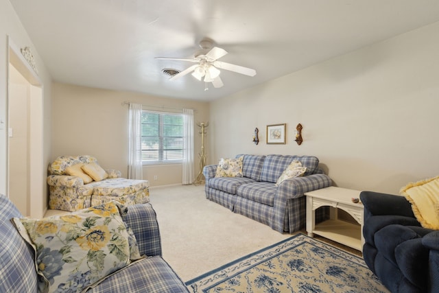 living room featuring a ceiling fan, visible vents, and light colored carpet