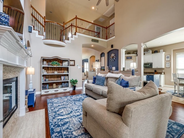 3226 Appleblossom Dr, Frisco, TX 75033 - living area featuring arched walkways, a ceiling fan, a tile fireplace, a towering ceiling, and baseboards