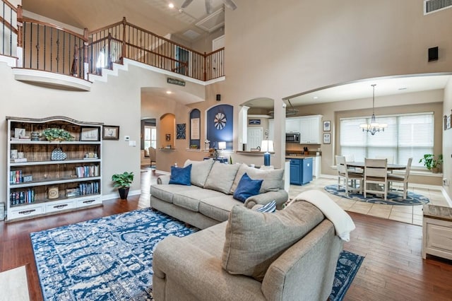 3226 Appleblossom Dr, Frisco, TX 75033 - living room featuring arched walkways, a chandelier, a towering ceiling, baseboards, and wood finished floors