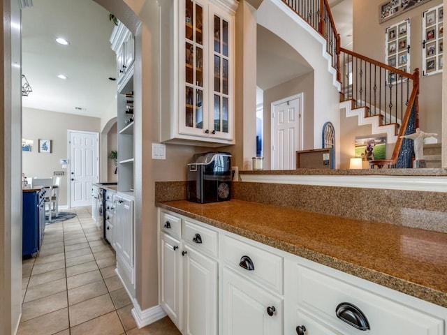 3226 Appleblossom Dr, Frisco, TX 75033 - kitchen with light tile patterned flooring, arched walkways, glass insert cabinets, white cabinets, and baseboards