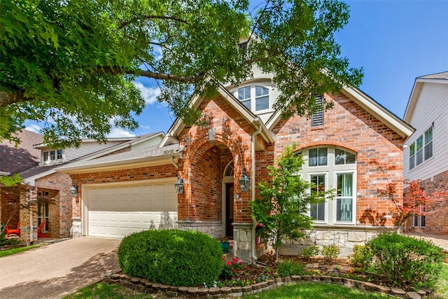 english style home with a garage, brick siding, stone siding, and concrete driveway