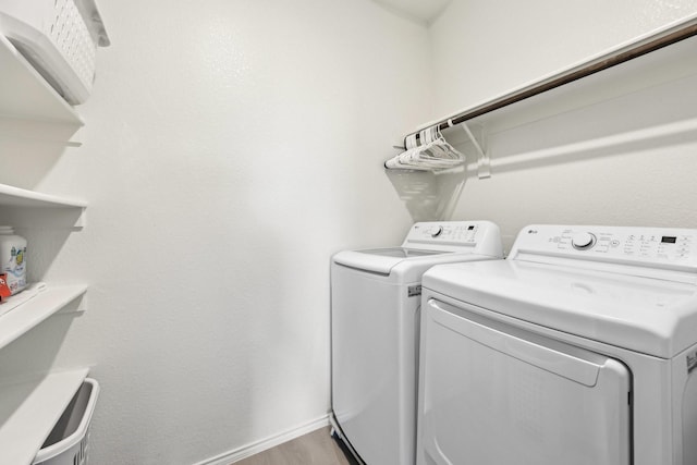 washroom with washing machine and dryer, baseboards, light wood finished floors, and laundry area