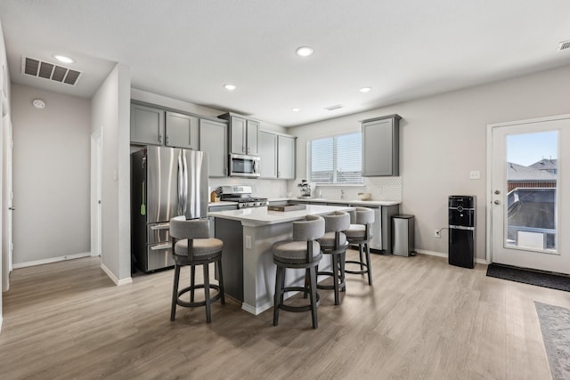 kitchen featuring visible vents, a kitchen bar, decorative backsplash, a kitchen island, and appliances with stainless steel finishes