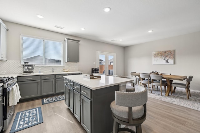 kitchen with tasteful backsplash, stainless steel range with gas stovetop, a breakfast bar area, and gray cabinetry