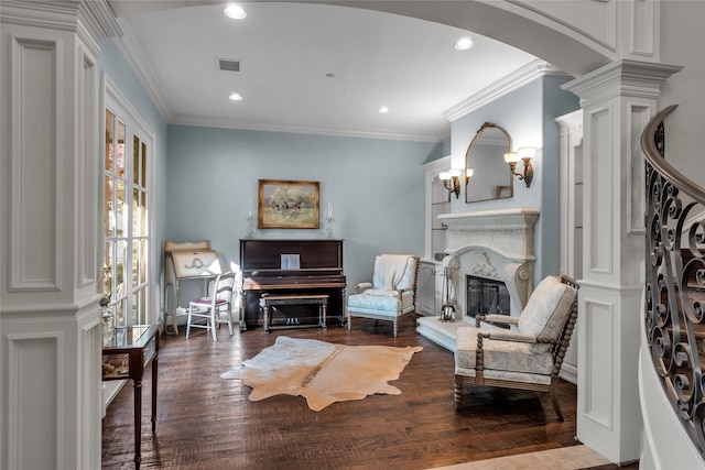 sitting room with arched walkways, wood finished floors, visible vents, and decorative columns
