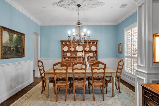 dining area with an inviting chandelier, wood finished floors, visible vents, ornamental molding, and arched walkways