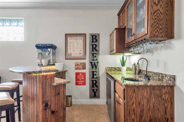 bar with baseboards, wet bar, a sink, and light carpet