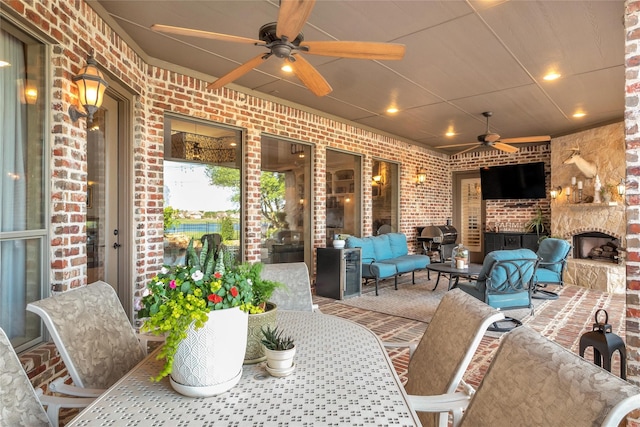 view of patio with outdoor dining space, ceiling fan, and an outdoor living space with a fireplace
