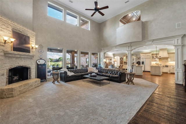 living room featuring crown molding, ceiling fan, visible vents, decorative columns, and a towering ceiling