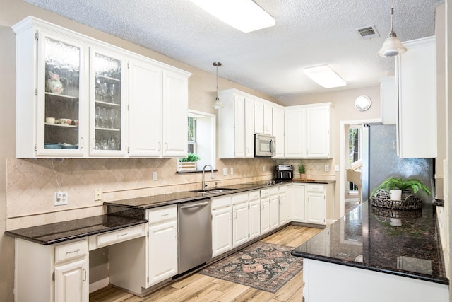 kitchen featuring decorative light fixtures, appliances with stainless steel finishes, a sink, and light wood-type flooring