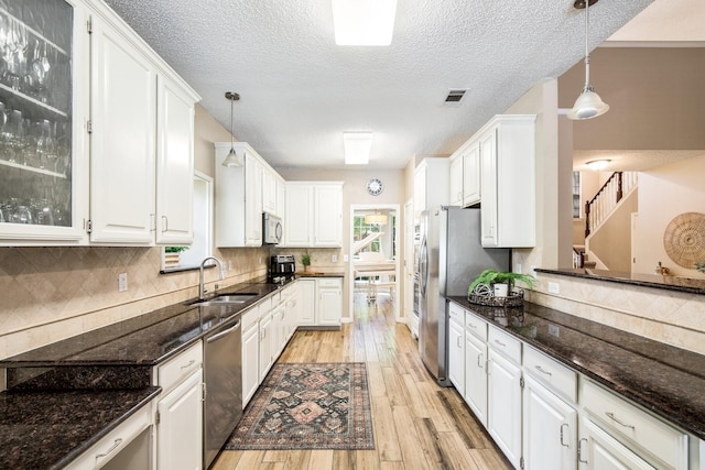 kitchen featuring stainless steel appliances, visible vents, a sink, light wood-type flooring, and white cabinetry