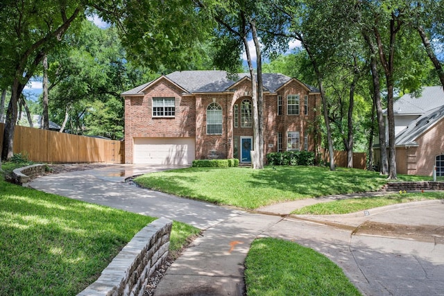 bi-level home with fence, an attached garage, driveway, brick siding, and a front yard