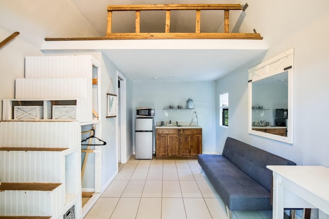 kitchen with stainless steel microwave, a sink, tile patterned floors, and fridge