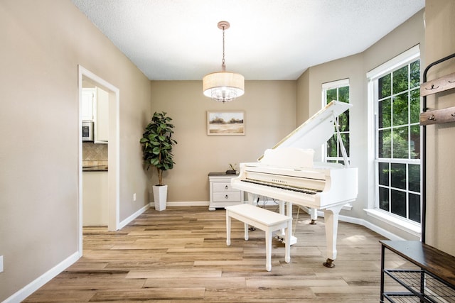 living area featuring baseboards, a chandelier, and light wood-type flooring