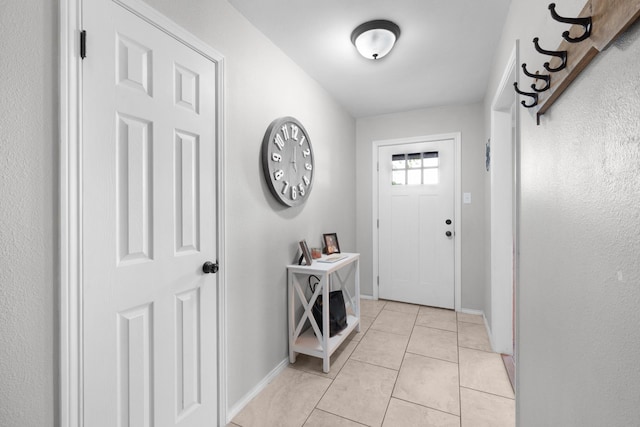 doorway with baseboards and light tile patterned floors