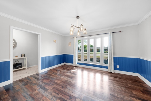 spare room with wainscoting, an inviting chandelier, ornamental molding, and wood finished floors