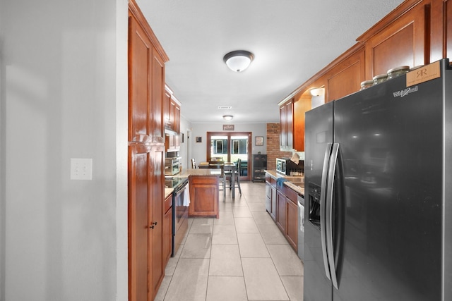 kitchen with brown cabinets, appliances with stainless steel finishes, and light tile patterned flooring