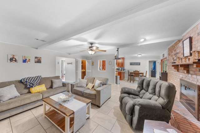 living area featuring visible vents, a ceiling fan, ornamental molding, a brick fireplace, and light tile patterned floors