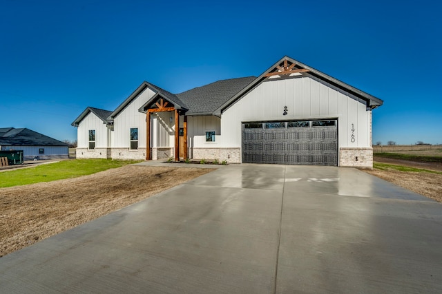 modern farmhouse style home featuring a garage, driveway, board and batten siding, and a front lawn