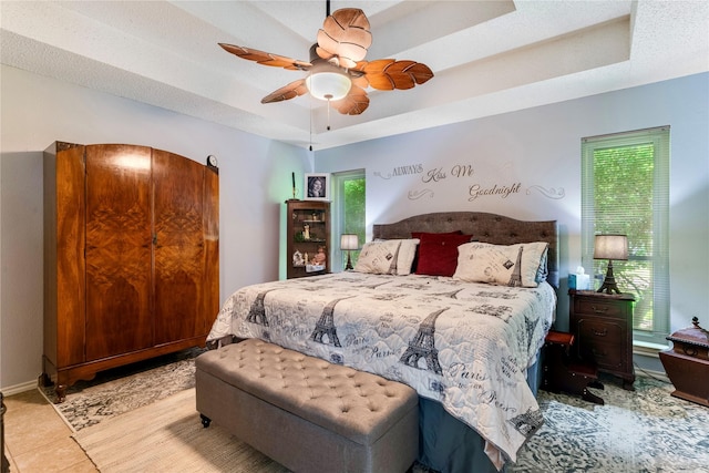 259 Deer Valley Dr, Powderly, TX 75473 - bedroom with tile patterned floors, a ceiling fan, a tray ceiling, and baseboards