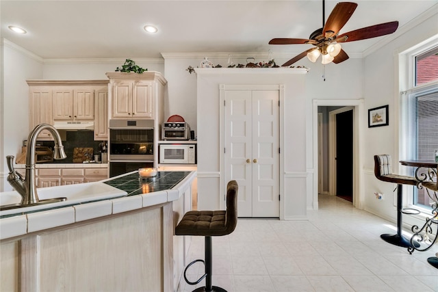 259 Deer Valley Dr, Powderly, TX 75473 - kitchen with tile counters, a sink, double oven, ceiling fan, and white microwave