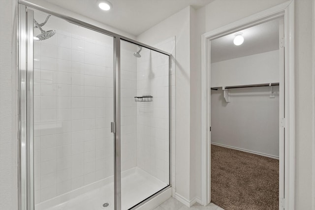 full bath featuring a shower stall, a spacious closet, and baseboards
