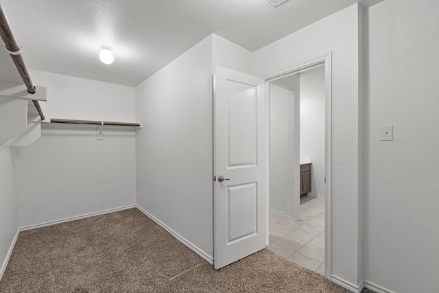 walk in closet with light colored carpet and light tile patterned flooring