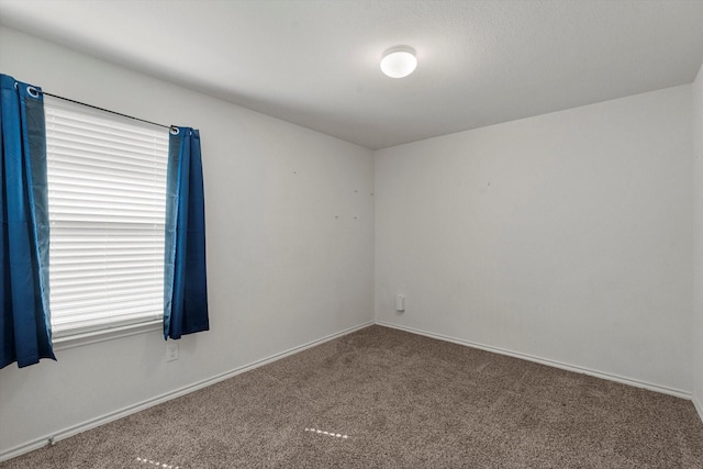 spare room featuring carpet and baseboards