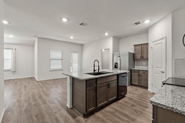 kitchen featuring a sink, dishwasher, a healthy amount of sunlight, light wood-style flooring, and visible vents