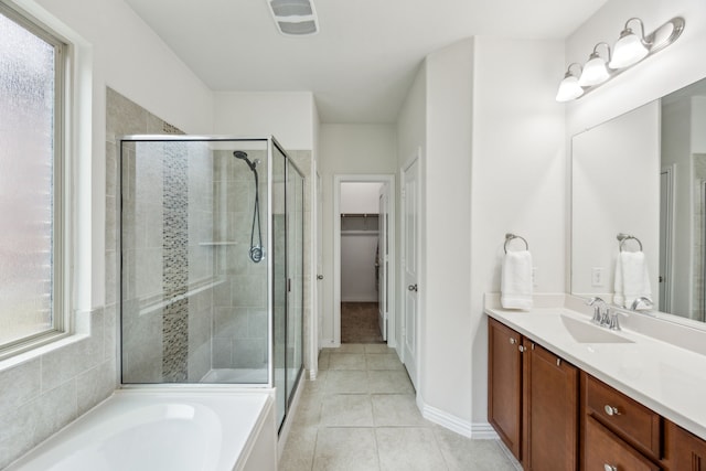 bathroom featuring vanity, tile patterned flooring, a walk in closet, and a stall shower