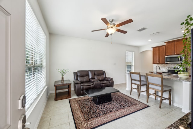 living area with baseboards, visible vents, ceiling fan, and light tile patterned flooring