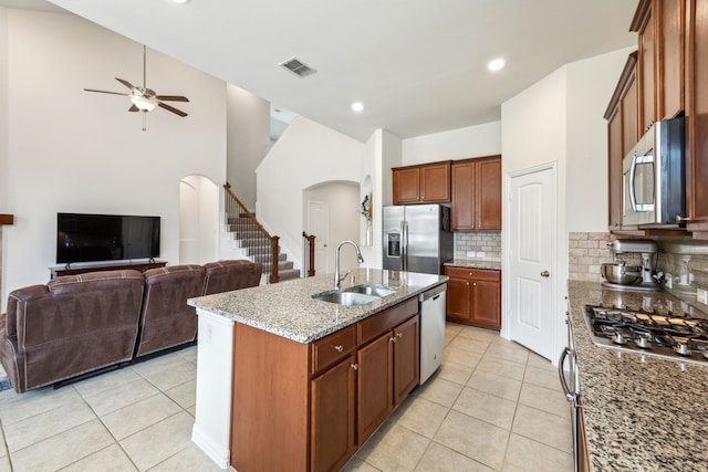 kitchen with a sink, light tile patterned floors, ceiling fan, arched walkways, and appliances with stainless steel finishes