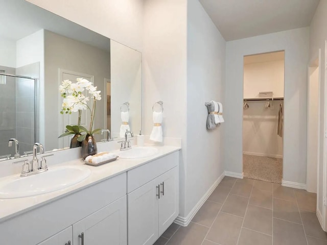bathroom with double vanity, a sink, a shower stall, and a walk in closet