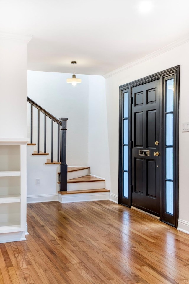 foyer entrance featuring stairs, crown molding, and light wood-style flooring