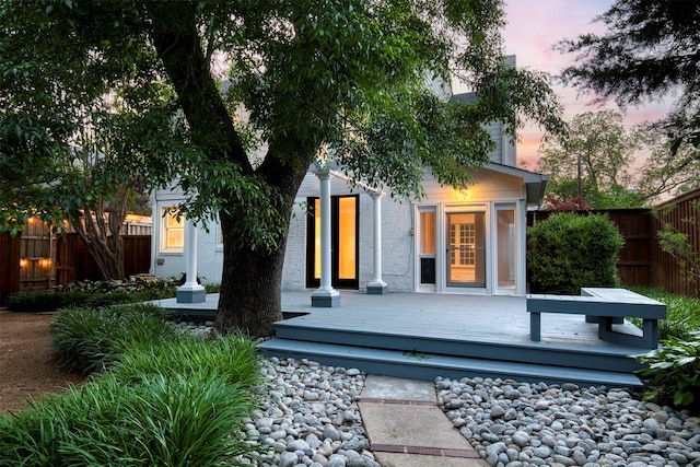 back of property at dusk with fence and a wooden deck